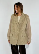 Saco color beige con solapas, cierre de dos botones, bolsillos delanteros con solapa y mangas de punto acanalado.