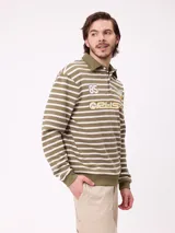 Polo de manga larga con diseño a rayas horizontales en azul marino y blanco. Presenta cuello tipo polo con cierre de botones, estampado frontal con el logo de la marca y el número 85, y puños elásticos.