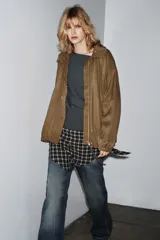 Chaqueta tipo bomber fluida color tostado, con cuello alto ajustable mediante cordones, cierre frontal con cremallera y botones a presión ocultos bajo solapa. Presenta mangas largas con puños elásticos, bolsillos delanteros y bajo con pliegues.