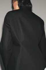 Blazer negro de mezcla de algodón, con cuello subido y manga larga. Cuenta con falsos bolsillos de vivo en el delantero y cierre frontal con alamares a tono.