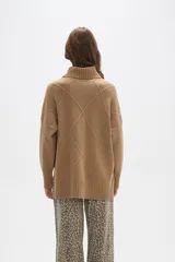 Sweater de tejido de punto color beige, con cuello polera y diseño holgado. Presenta un patrón de rombos en relieve en la parte frontal y mangas largas con puños acanalados.