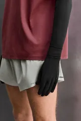 Guantes de running negros, ligeros y ajustados, confeccionados en tejido técnico con mezcla de lana. Cuentan con función táctil en los dedos y un enganche lateral de seguridad para unirlos.