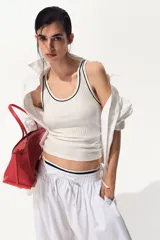 Musculosa blanca de punto acanalado suave, con escote en U y ribetes negros en contraste en el cuello y las sisas.