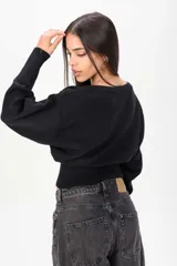 Sweater negro de punto con diseño holgado, escote bote y cintura ajustada con elástico ancho.
