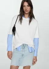 Minifalda de jean celeste con cierre de cremallera y botón, tiro medio, bolsillos delanteros y traseros, diseño recto y bajo deshilachado.