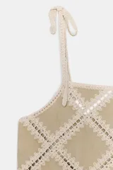 Top de escote recto color beige con tirantes finos ajustables con lazadas. Presenta un diseño con apliques de tejido tipo crochet en patrón geométrico de rombos.
