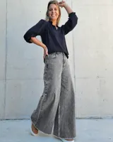 Jean wide leg de tiro alto, color gris con efecto lavado. Presenta un diseño de pierna ancha, cierre frontal con botón y ruedo desflecado.