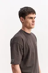 Remera boxy de algodón color beige, de silueta amplia y corta, con mangas cortas y pequeño estampado en el pecho.