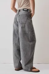 Jeans de corte barrel en tono gris deslavado, con diseño amplio y tachas decorativas a lo largo de las costuras laterales y los bolsillos delanteros.
