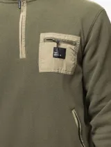 Buzo de polar gris oscuro con cuello alto y medio cierre frontal. Presenta un bolsillo en el pecho con cierre y detalles en nylon, además de bolsillos laterales con cierre.