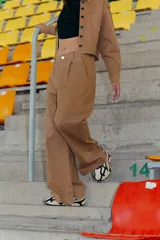 Pantalón camel de gabardina elastizada, corte sastrero, tiro bajo, con bolsillos delanteros, botón metálico y tajo en el lateral interno.