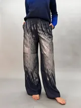 Pantalón de lana azul con estampado abstracto en tonos plateados. Tiro alto, corte amplio y bolsillos laterales ocultos.