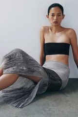 Falda midi de tiro medio, color gris, confeccionada en mezcla de lyocell y viscosa, con detalle de apliques de lentejuelas y bajo de tejido transparente plisado con bordados florales.