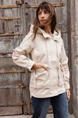 Gabardina liviana color beige con capucha, cierre frontal oculto y cintura ajustable mediante cordón. Presenta bolsillos delanteros amplios y mangas largas con puños rectos.