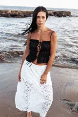 Top negro con breteles finos, escote recto con volantes y lazo ajustable en el centro.