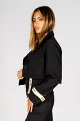 Blazer negro corto con solapas, cierre con un botón y mangas largas con puños con cinta blanca con la inscripción "Craft Punk".