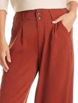 Pantalón tipo palazzo de corte ancho y fluido, confeccionado en tejido sastrero. Presenta tiro alto con doble abotonadura frontal, pinzas decorativas y cintura elástica en la parte posterior. Incluye bolsillos laterales funcionales.