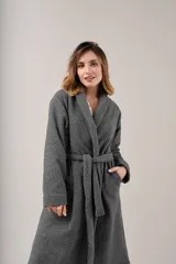 Bata de polar gris con textura labrada, diseño cruzado con lazo ajustable en la cintura, bolsillos laterales y mangas largas.