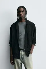 Camisa de hombre de corte relaxed fit, color negro, con textura de cuadros en relieve. Presenta cuello solapa, manga larga con puño abotonado y cierre frontal de botonadura.