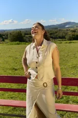 Top beige sin mangas con cuello solapa, escote en V y cierre frontal de botones carey.