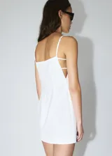 Vestido corto blanco de tirantes finos con escote recto y detalle de tiras cruzadas en la espalda.