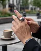 Anillo de acero de diseño bombé, con patrón geométrico esmaltado en tonos negro y gris oscuro.