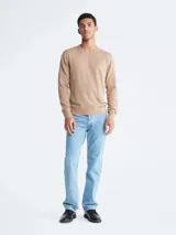 Sweater de punto color beige melange, de manga larga y cuello redondo, con un pequeño monograma bordado en el pecho.