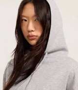 Saco color crema, de corte slim, confeccionado en algodón con viscosa certificada, con cuello con capucha y cordón ajustable, cierre frontal con cremallera y forro de fleece.