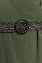 Vestido midi verde militar de cuello halter con escote en V cruzado y espalda descubierta. Cuenta con pliegues laterales, bajo asimétrico y un cinturón incorporado con hebilla redonda oscura.