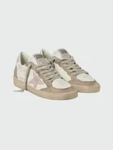 Championes Golden Goose modelo Ballstar, de cuero blanco con detalles en gamuza beige y estrella lateral en color rosa. Presentan un diseño desgastado característico de la marca, con cordones al tono y etiqueta con logo en la lengüeta.