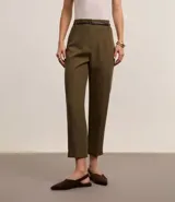 Pantalón de sastrería corte carrot, color beige, con cintura alta, pinzas frontales y cinturón fino incorporado con hebilla metálica.