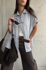 Camisa de manga corta con diseño a rayas celestes y blancas, cuello clásico y cierre frontal de botones.
