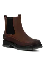Botín tipo Chelsea de cuero color marrón, con paneles elásticos laterales negros y suela robusta de poliuretano con base gris traslúcida.