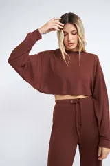 Buzo corto de tejido rib en color verde militar, con mangas largas y cuello redondo. Presenta un diseño holgado y cropped.