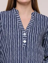 Blusa holgada de color verde con diseño de rayas verticales blancas, escote en V con cuello mao y pechera corta con botones. Mangas tres cuartos regulables y bajo redondeado.