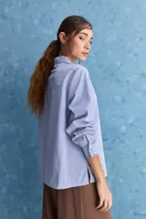 Camisa de rayas blancas y azules con cuello mao decorado con volados sutiles, cierre frontal de botones y mangas largas.