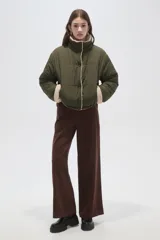 Campera puffer de corte holgado en color verde militar, con cuello alto y cierre frontal a presión. Presenta detalles de corderito en el cuello, puños y borde frontal, con bolsillos laterales.