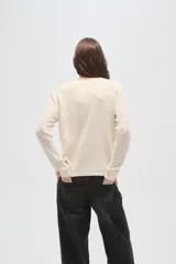 Sweater de punto color natural con diseño de ochos, cuello redondo y mangas largas de calce holgado.