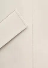Parka de corte recto en mezcla de lana color blanco, con cuello embudo grande, mangas largas con trabillas, dos bolsillos de solapa laterales y cierre delantero con botones.