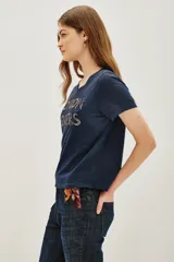 Remera azul marino de algodón con cuello redondo y mangas cortas. Presenta la frase 'LONDON LOVERS' bordada en el frente con cuentas metálicas.