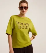 Remera verde de mangas cortas, confeccionada en malla, con cuello redondo y lettering "happy hour" estampado en el pecho.