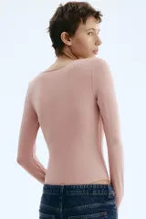 Body de manga larga confeccionado en punto elástico color rosado, con diseño colaless, escote cuadrado y cierre con botones a presión en la parte inferior.