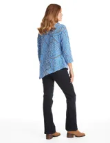 Buzo de tejido soft labrado con diseño floral, cuello volcado con detalle de botones en la solapa, mangas tres cuartos con hombros caídos y ruedo asimétrico en punta.