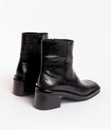 Botín de cuero con estampado de piel de serpiente en tonos blanco y negro, con puntera cuadrada y tacón bloque bajo.