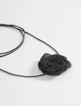 Gargantilla de cordón fino negro con detalle de flor de tela en el centro.