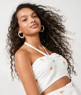 Blusa corta blanca de algodón con bordado de palmeras color naranja, escote halter y espalda descubierta.