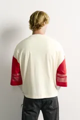 Camiseta boxy fit de cuello redondo y manga por debajo del codo. Presenta un diseño bicolor en tonos blanco off-white y rojo, con estampado y parches frontales con efecto lavado vintage y franjas en las mangas.
