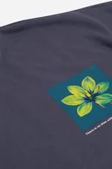 Buzo de felpa color beige de manga corta, con escote redondo y estampado de una flor amarilla y azul en el frente.