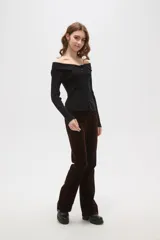 Top de punto acanalado color negro, con escote estilo strapless y cierre frontal con botones. Presenta mangas largas y un ajuste al cuerpo.