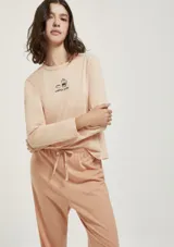 Pijama compuesto por una remera de manga larga color rosado con estampa frontal pequeña y un pantalón largo de textura acanalada en tono rosado con cintura elástica y lazo de ajuste.